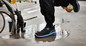 Arbeiter mit Sicherheitsschuhen tritt in Pfütze