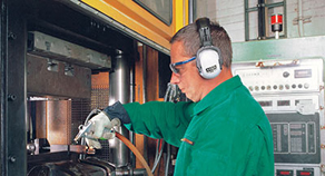 Arbeiter an der Maschine mit Gehörschutzkapsel