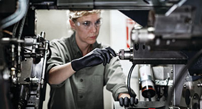 Arbeiterin mit Schutzhandschuhen vor einer Maschine